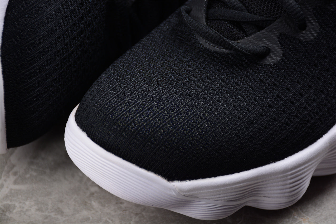 Black sneaker with white sole on a gray surface