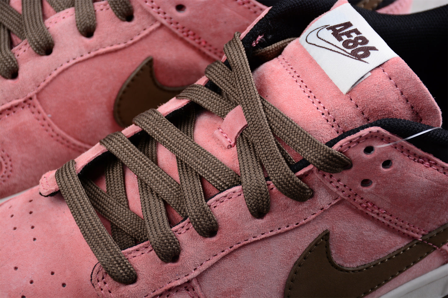 Pink sneakers with brown laces and a visible brand logo on a close-up view.