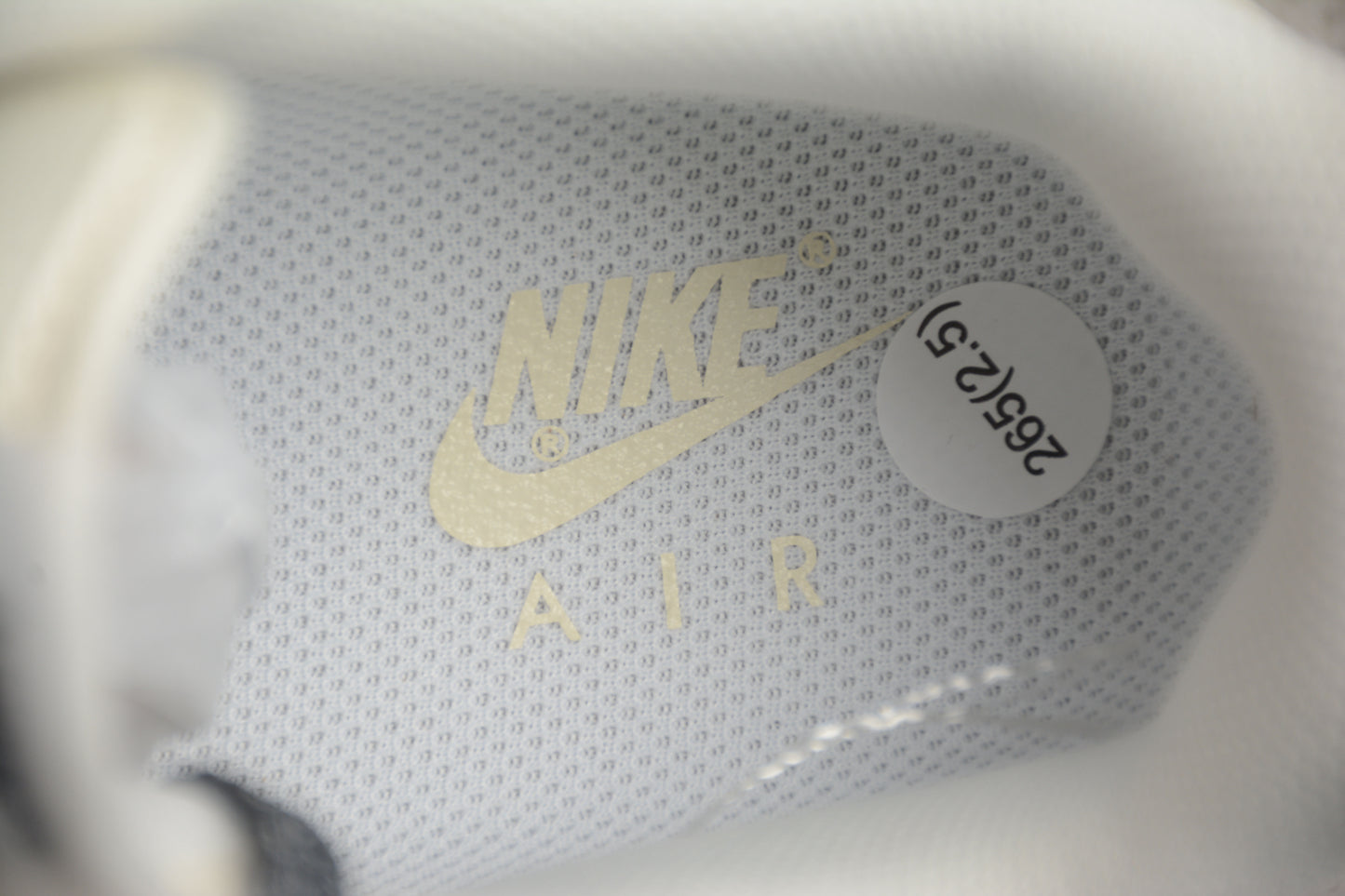 Close-up of a Nike Air shoe with gold logo and white sole.
