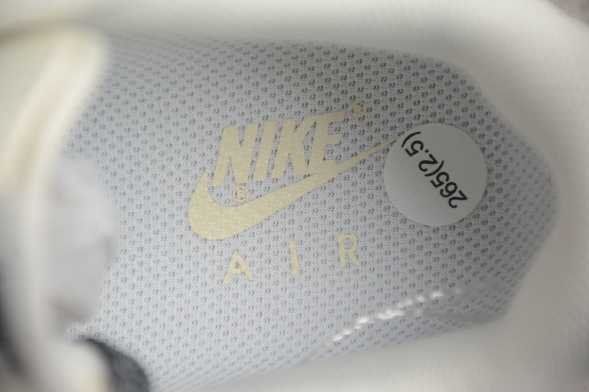 Close-up of a Nike Air shoe with gold logo and white sole.