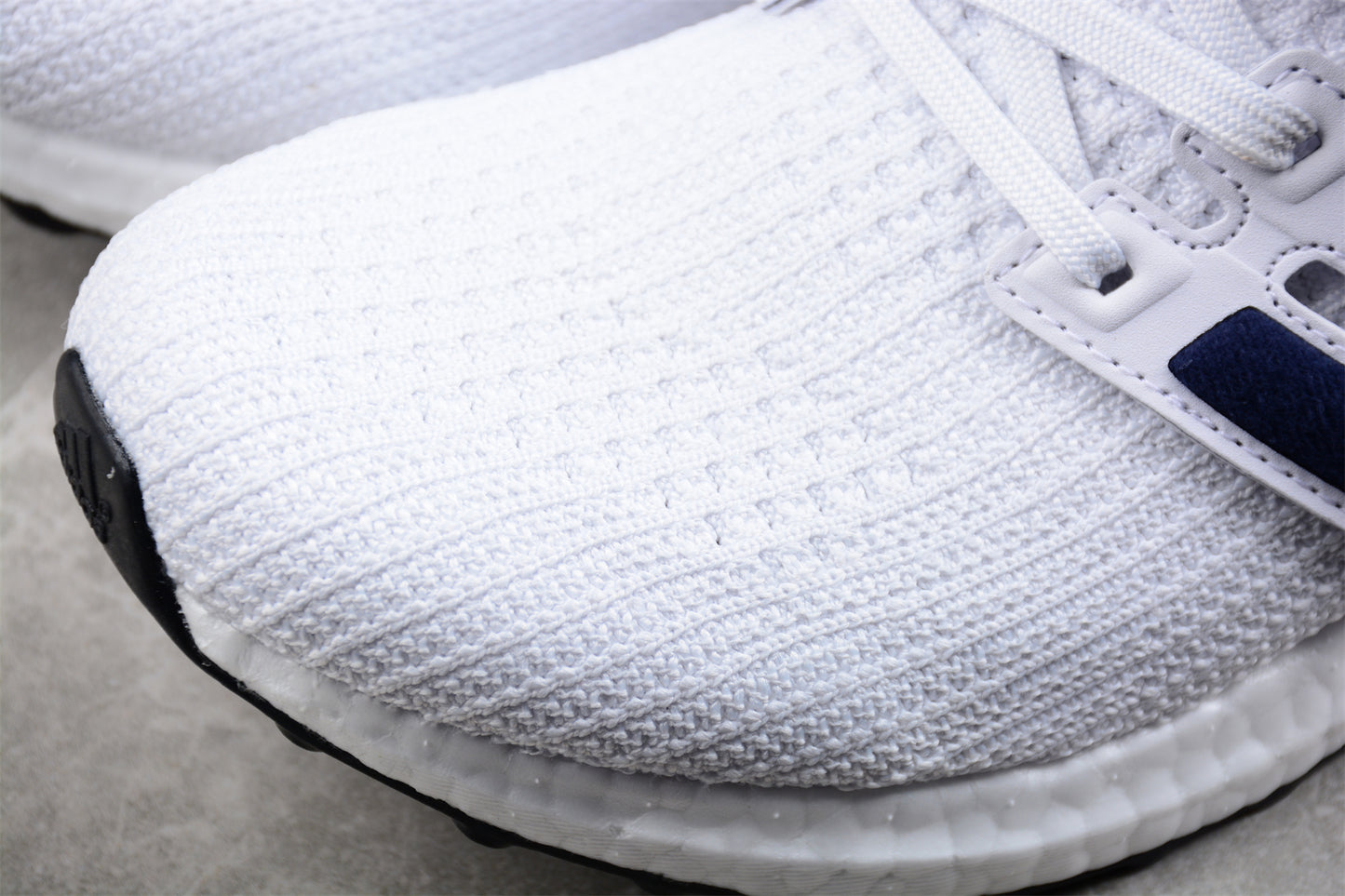 Close-up of a white athletic shoe with a textured sole on a gray surface