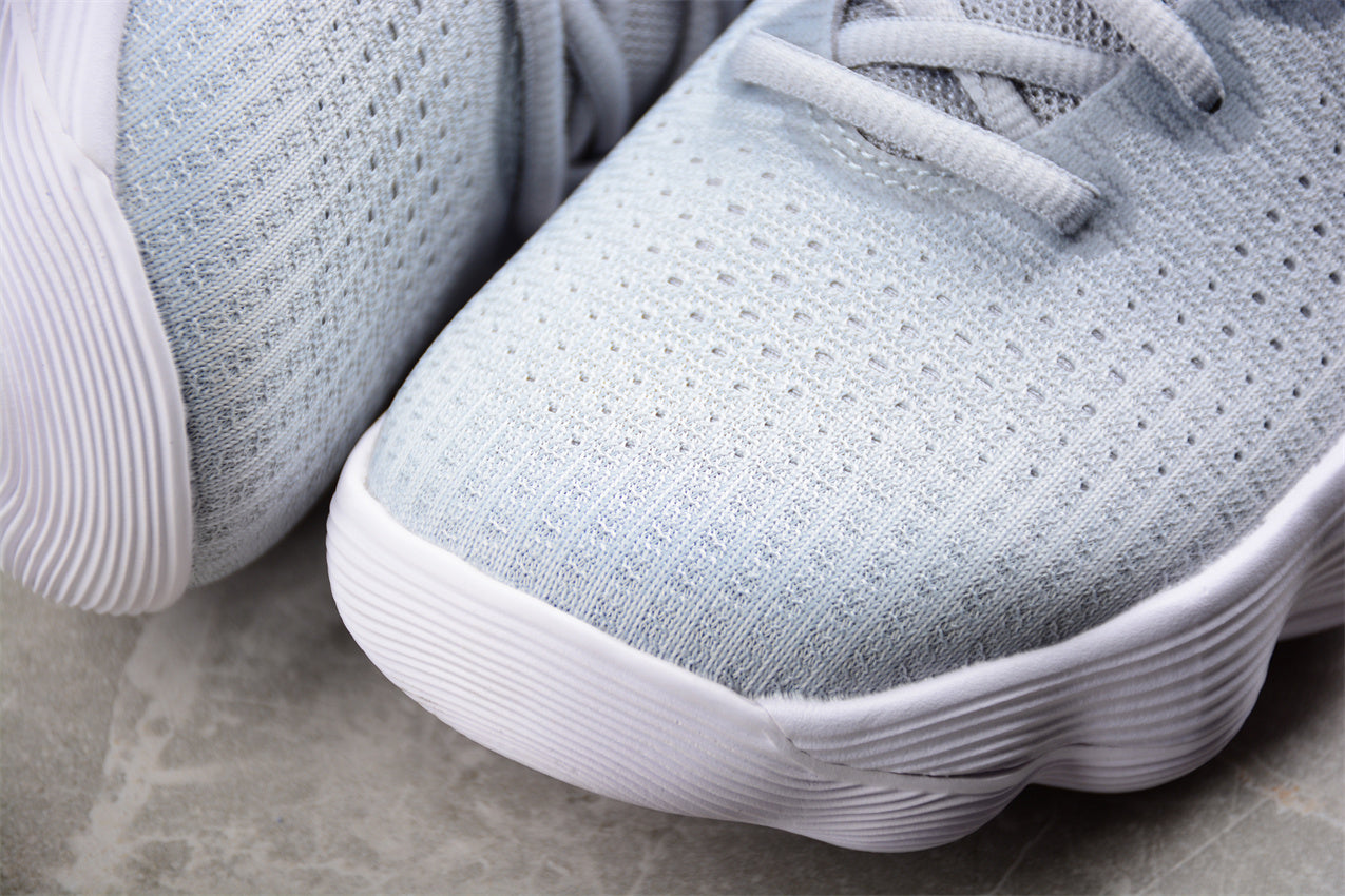 Close-up of gray athletic shoes with white soles on a stone surface