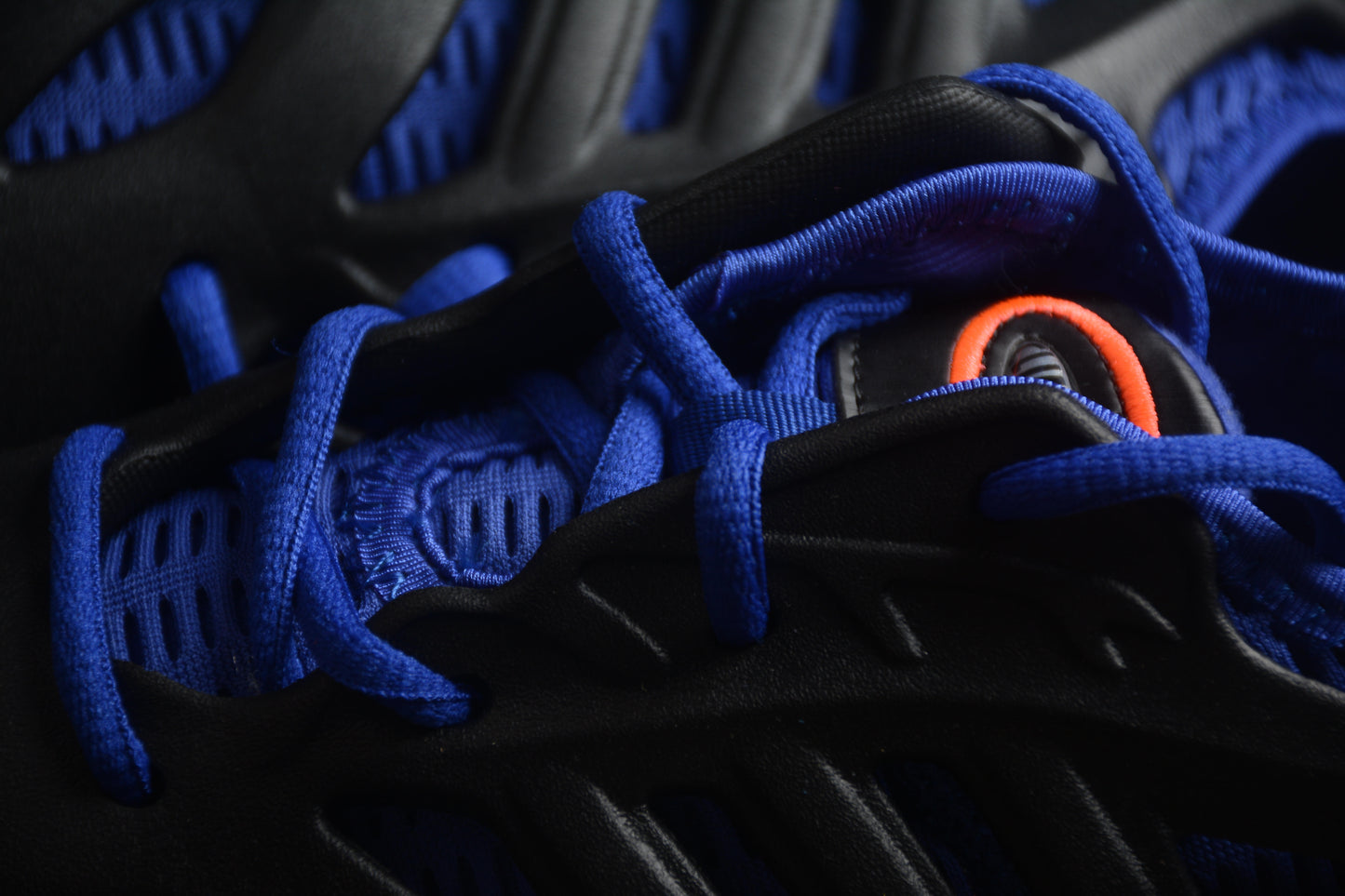 Close-up of black and blue sneakers with orange accents on a dark background