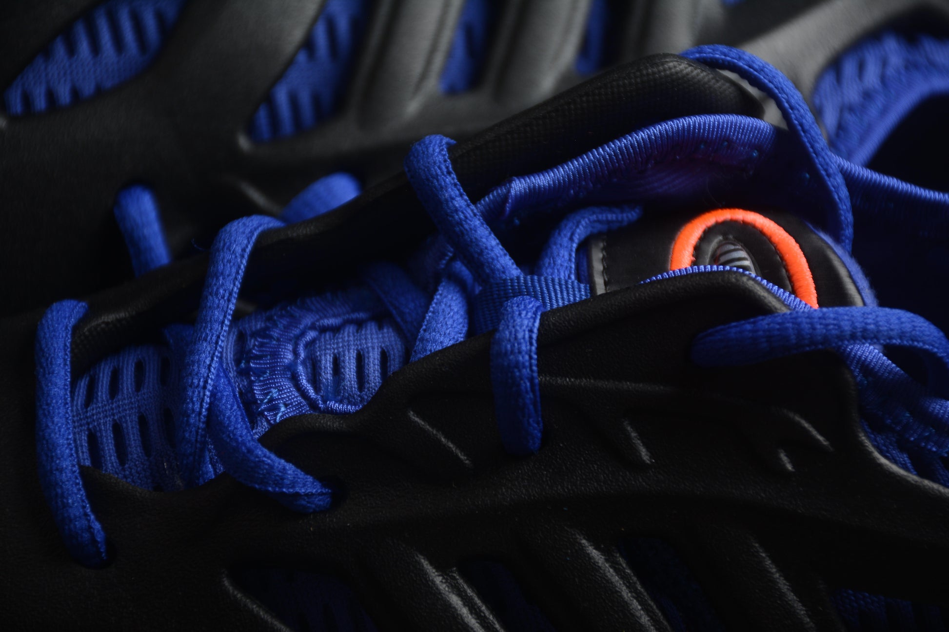 Close-up of black and blue sneakers with orange accents on a dark background